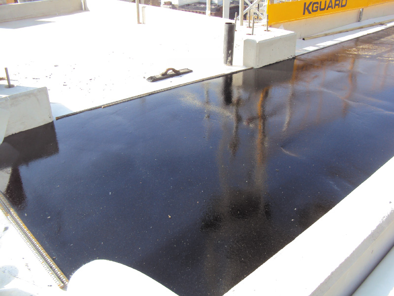 Contractors applying IKO Permascreed LI to prepare a roof deck for waterproofing