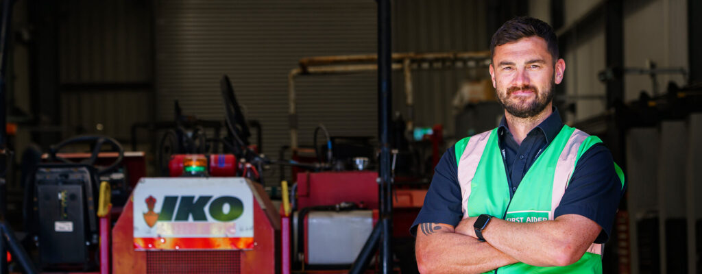 Photo of an IKO PLC employee wearing branded overalls in the production area of the Grangemill manufacturing site